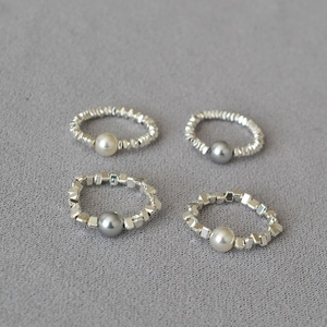 Detail of silver stretch rings with irregular beads and white or dark grey pearls