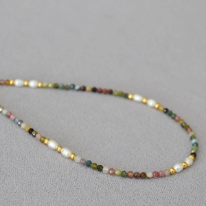Macro detail of natural tourmaline beads and rice pearls on a fine gold-plated necklace