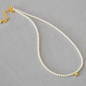 Collier de perles élégant avec perle dorée centrale et chaîne réglable sur fond gris
