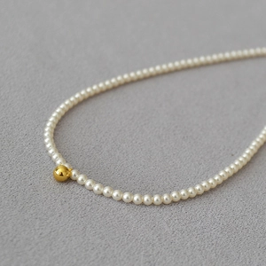 Vue macro d'un collier de perles blanches élégant avec une perle centrale en or 18K