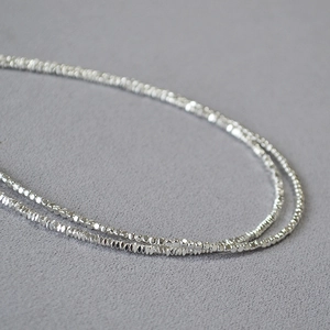 Vue macro détaillée des perles argentées à facettes sur une chaîne de collier fine