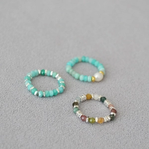 Detailed view of elastic beaded rings set with amazonite stones and a freshwater pearl