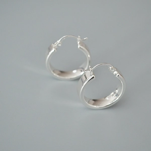 Vue macro de boucles d'oreilles créoles larges en argent avec une finition polie miroir
