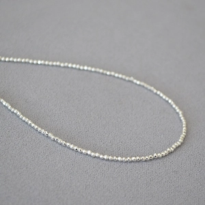 Minimalist silver faceted bead necklace with high-shine metallic finish and delicate craftsmanship