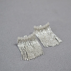 Détail de boucles d'oreilles à franges argentées avec perles métalliques
