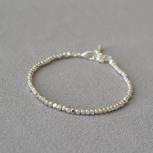 Detailed macro view of silver irregular beaded bracelet with lobster clasp and extender chain