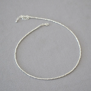 Close-up of a delicate silver beaded necklace with lobster clasp and extension chain