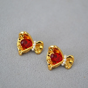 Détail macro de boucles d'oreilles fleurs dorées avec zircon rouge et perles