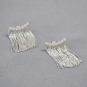 Détail de boucles d'oreilles à pampilles argentées avec clous en métal géométriques