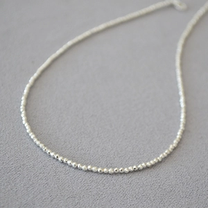 Macro view of dainty silver faceted bead necklace showing refined metallic craftsmanship