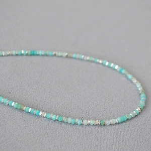 Macro view of blue amazonite faceted beads and silver spacer beads on a textured fabric