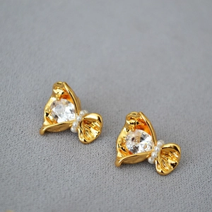 Gros plan de boucles d'oreilles fleurs dorées avec cristaux et perles blanches
