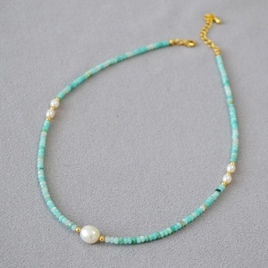 Elegant necklace with green amazonite beads and freshwater pearls on grey fabric