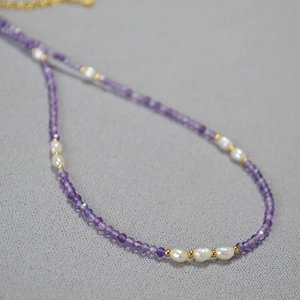 Elegant lavender amethyst and baroque pearl beaded necklace with gold spacers on grey fabric