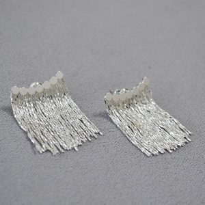 Vue détaillée des boucles d'oreilles à pompons argentés avec design à maillons disques