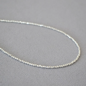 Macro shot of minimalist sparkling faceted silver beads on a delicate chain necklace