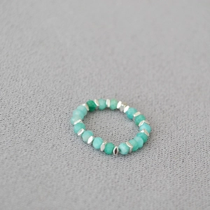Detail of beaded elastic ring with green faceted stones and silver-toned diamond spacers