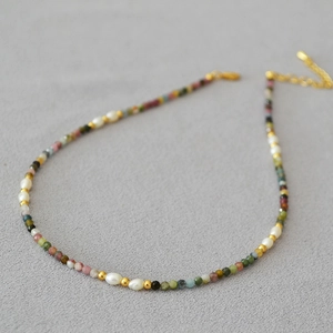 Detailed macro of colorful tourmaline stones and freshwater pearls with gold lobster clasp