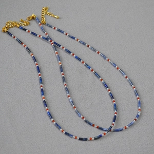 Détail du collier de perles avec tubes de lapis-lazuli bleus et pierres d'agate rouge sur tissu