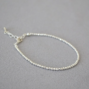 Macro view of minimalist faceted silver beads necklace with lobster clasp and extender