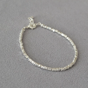 Detail of silver beaded bracelet featuring irregular multifaceted beads and lobster clasp