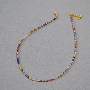 Détail macro du collier de perles facettées colorées avec fermoir mousqueton doré et chaîne