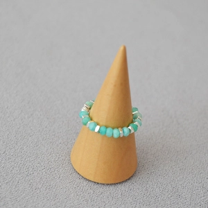 Detailed shot of handmade Amazonite beaded ring with silver spacer beads on wood stand