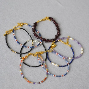 Close-up of stacked natural gemstone bracelets with garnet, lapis lazuli and pearls