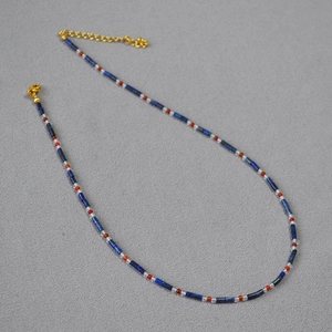 Détail d'un collier en perles de lapis-lazuli bleu, agate rouge et fermoir doré
