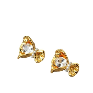 Boucles d'oreilles fleur dorées avec zircon clair et perles blanches sur fond blanc