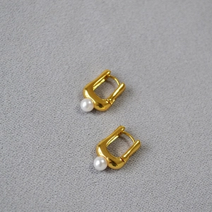 Gros plan détaillé de boucles d'oreilles en U dorées avec perles blanches nacrées