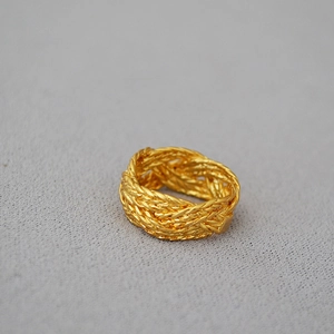 Macro detail of gold-plated braided ring showing intricate woven metal texture