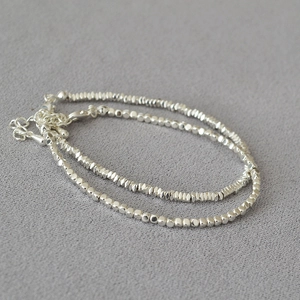 Detailed view of a silver double-layered beaded bracelet with a lobster clasp closure