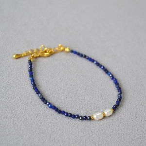 Detail of beaded bracelet with dark blue lapis beads and two white freshwater pearls