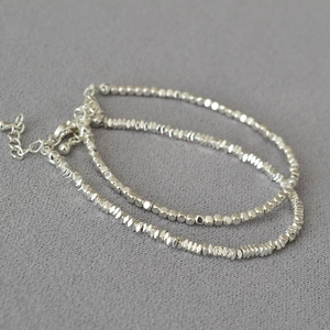 Detailed view of silver beaded bracelet with irregular faceted beads and lobster clasp