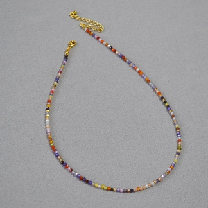 Détail macro des perles facettées colorées et du fermoir doré sur le collier