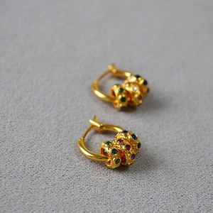 Détails macro de boucles d'oreilles créoles en laiton doré avec pierres de zircone colorées