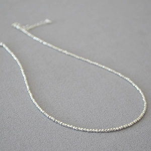 Minimalist faceted silver beaded necklace with shiny metallic finish and extender chain