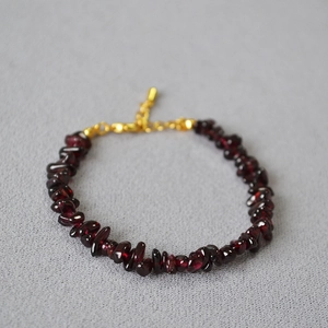 Macro view of irregular garnet stone beads with gold lobster clasp and adjustable chain