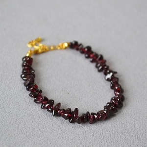 Close-up of deep red garnet stone bracelet with golden lobster clasp and extender