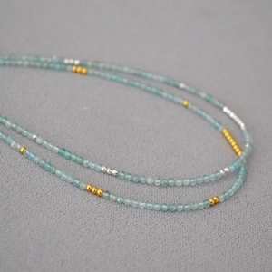 Macro shot of minimalist aquamarine beaded necklace with gold and silver accents