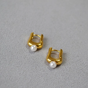 Détail de boucles d'oreilles créoles dorées en U avec perles blanches élégantes