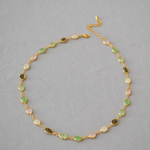 Macro detail of multicolored oval crystals on a gold-plated brass chain necklace