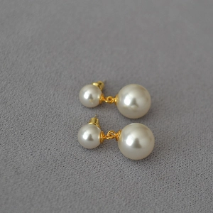 Detailed view of elegant double faux pearl earrings with golden chain on velvet surface