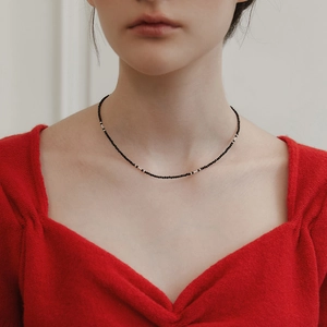 Detail einer eleganten Kette aus schwarzen facettierten Perlen und Goldperlen am Model