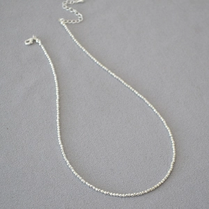 Macro detail of silver faceted beads necklace with lobster clasp and extension chain