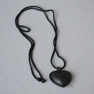 Vue macro du pendentif cœur en cuir noir avec cordon tressé et bordure texturée
