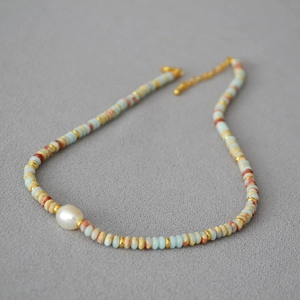 Detail of bohemian beaded necklace with blue stones, rust beads and a white center pearl