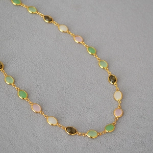 Macro shot of multi-color faceted crystal gemstones on gold-plated brass necklace chain