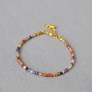 Detailed view of faceted natural stone and pearl beaded bracelet with gold chain